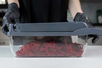 Chef's gloved hands expertly operating a modern kitchen vegetable grater, efficiently preparing...