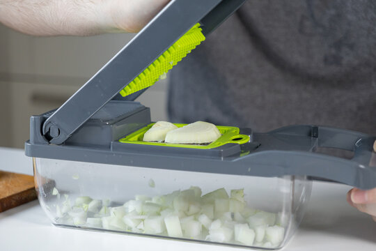 Person uses a multi-functional vegetable chopper to dice fresh onion, demonstrating kitchen efficiency and modern convenient food preparation for a busy home cook