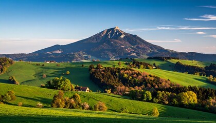 Majestic Mountain Landscape with Rolling Green Hills Under Clear Blue Sky