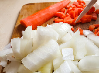Slicing carrots with a knife in the kitchen. Woman shredding carrots on a kitchen board.
