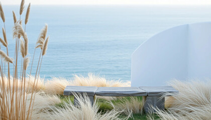 A single stone bench faces the endless sea, framed by bleached grass and the soft curve of a white limewashed wall.
