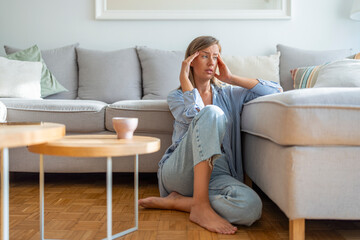 Woman Sitting on Floor Feeling Stressed in a Comfortable Home Interior Setting