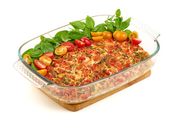 Tomato casserole with basil leaves in glass pan isolated on white background