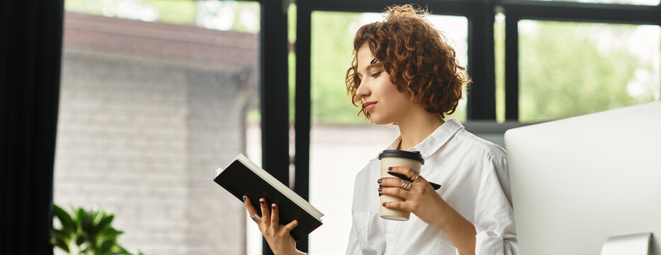 Young businesswoman immersed in work while enjoying coffee in modern office setting