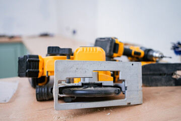 Professional-grade circular saw and cordless drill lie on a workbench amidst sawdust, indicating...