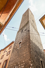 Ancient stone towers in the city of Bologna in Italy The sky is light blue and slightly cloudy and The photo shows parts of neighboring houses