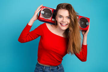 Cheerful young woman in a red top with a vintage stereo cassette player on a vibrant blue background