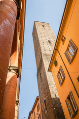 Ancient stone towers in the city of Bologna in Italy The sky is light blue and slightly cloudy and The photo shows parts of neighboring houses