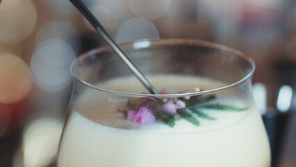 Closeup mixed passion fruit and sweet liquor cocktail decorated adding pink flower on top, making...