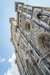 A tall building of Florence Cathedral with a clock tower and a blue sky in the background