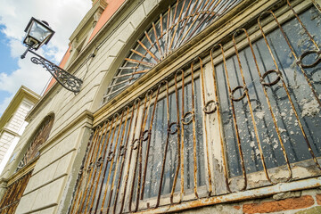 A window with a rusted iron bar and a lamp post in the background
