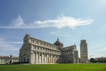 A large white building in Pisa Italy with a green roof and a large tower
