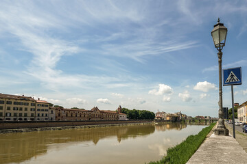 A city street in Pisa Italy with a river running through it