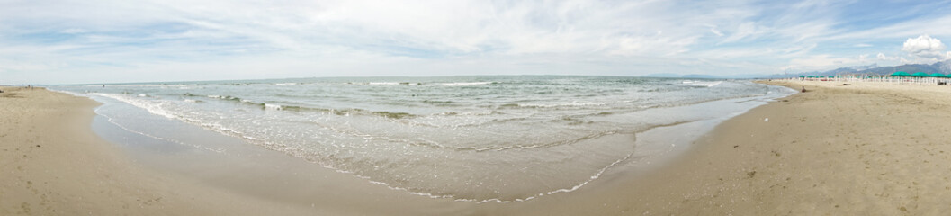 A beautiful beach with a clear blue ocean and a few people walking on the sand