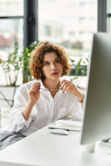 Curly haired businesswoman engaged in focused work in a modern office setting