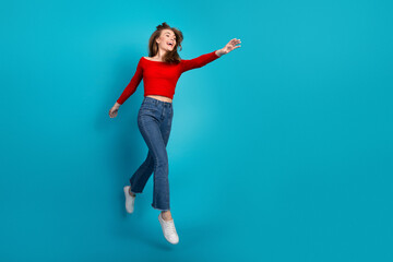 Happy young woman in casual fashion attire posing against blue studio background with positive...