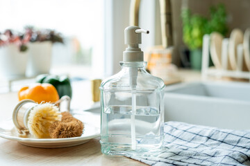 Plate with an ecobrush for washing dishes near the sink, soap in a glass bottle, a towel.