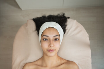 young woman with natural skin lying on spa bed after facial treatment, horizontal close-up, looking...