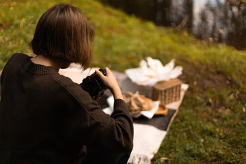 Woman taking photos of an outdoor fall picnic setup, documenting the seasonal details and rustic atmosphere.