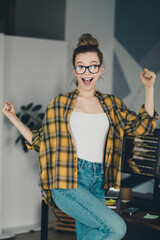 Excited young woman in a casual shirt celebrating success while working on a computer in a stylized...