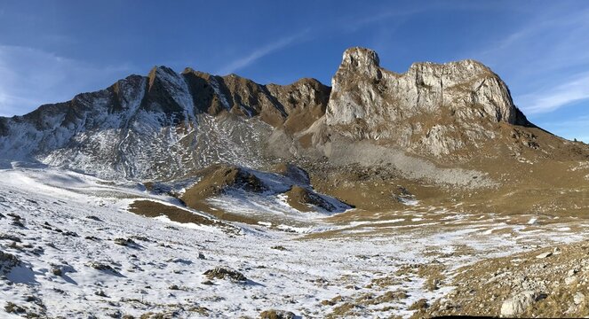 Mountain panorama in the Swiss mountains around Gurnigel and Gantrisch, lightly covered with snow in the clear golden morning or evening light, with blue sky and alpine scenery