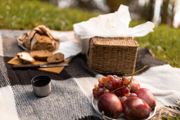 An inviting picnic scene laid out on the grass beside a calm lake, filled with food, textures, and warm light.