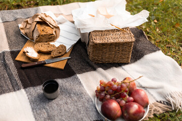 An inviting picnic scene laid out on the grass beside a calm lake, filled with food and fruit, textures, and warm light.
