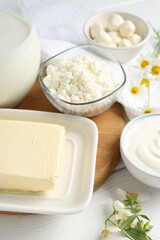 Fresh dairy products and flowers on white wooden table, closeup