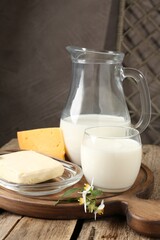 Different fresh dairy products and flowers on wooden table, closeup