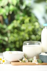 Different fresh dairy products and flowers on white table outdoors, closeup