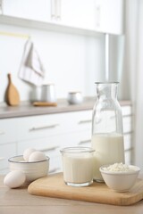 Different dairy products and eggs on wooden table in kitchen