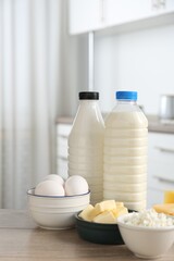 Different dairy products and eggs on wooden table in kitchen