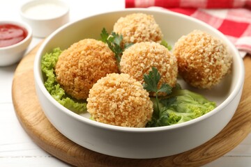 Delicious fried croquette balls with parsley and lettuce on white wooden table, closeup