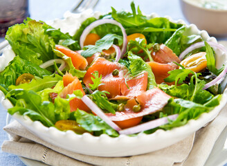 Smoked Salmon Salad with Mixed Greens, Onion, cherry tomatoes and Capers in White Bowl closeup view of healthy eating
