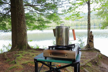 Morning coffee prepared in a percolator on the lakeshore of a campsite