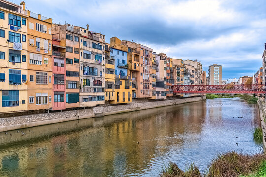Scenic view of Girona with the iconic Eiffel Bridge over the Onyar River, Spain. Colorful riverside buildings reflect in the calm water, showcasing historic European charm - Powered by Adobe