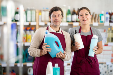 Man and girl sellers stands in trading hall of household store, wearied in apron stands in trading...