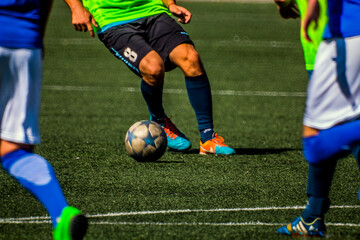 Legs of a soccer player with a gray star ball dribbling during a match	
