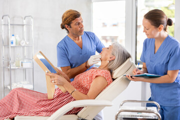 Man doctor palpates examines mature female patients facial skin and talks about need for lifting...