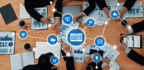 A top-view of a business meeting where a diverse team collaborates on data analysis. Various charts and digital elements surround the focus on ADS, highlighting teamwork. Amity