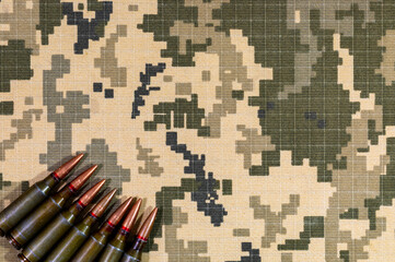 A cartridge from a machine gun on a background of pixel camouflage uniforms of the Ukrainian army. War in Ukraine