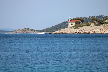 lighthouse prisnjak on rocky sea shore with blue ocean water, Kornati, Croatia