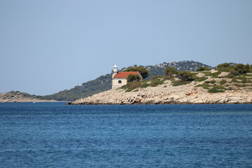 lighthouse prisnjak on rocky sea shore with blue ocean water, Kornati, Croatia