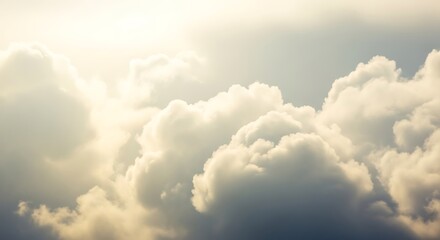 Soft golden sunlight illuminating fluffy white and gray cumulus clouds in a vast sky