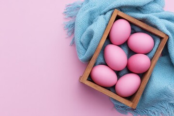 Pink eggs on a blue cloth in a wooden container Minimalist Easter theme Eggs in a box with a pink backdrop Top view