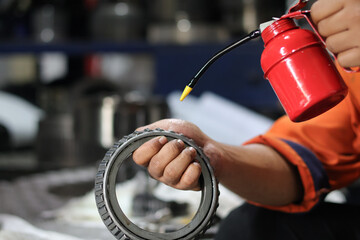 Close up male hand lubricating bearings with oil can. Industrial concept.