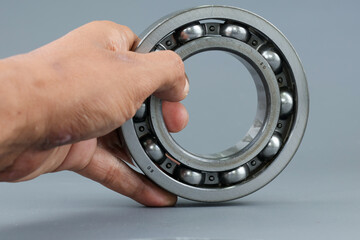 Hand holding Ball bearing isolated on dark background. Automotive spare part company. Heavy...