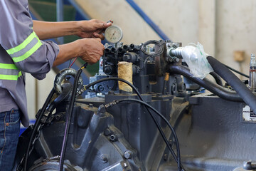 Obraz premium mechanic is checking and inspecting the Komatsu D155 transmission trouble while testing the transmission on the test bench in the workshop.