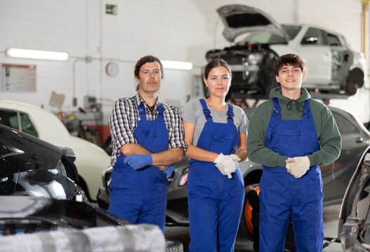 Portrait of team of auto mechanics near cars in a car service center