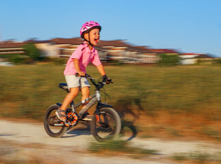  small brave three year old boy in a helmet rides a bicycle on a field road by himself